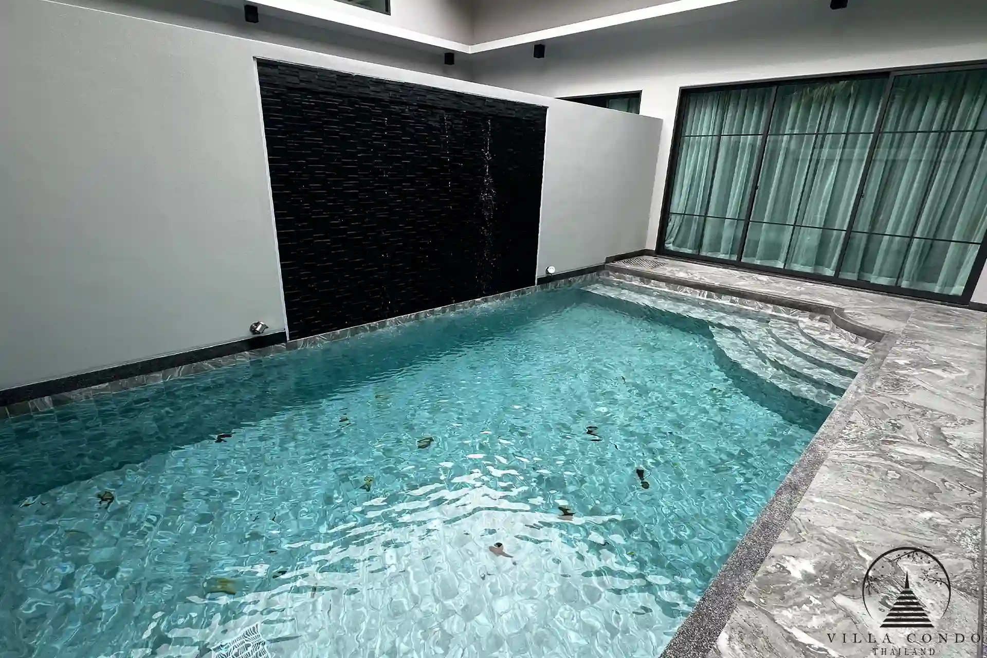 Private swimming pool with jacuzzi and waterfall feature.