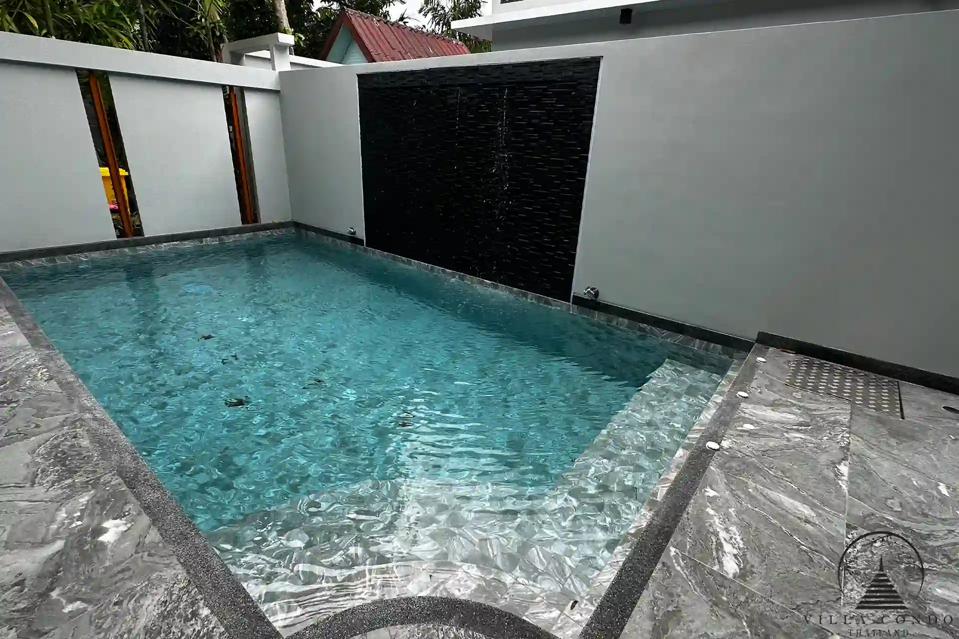 Private swimming pool with jacuzzi and waterfall feature.