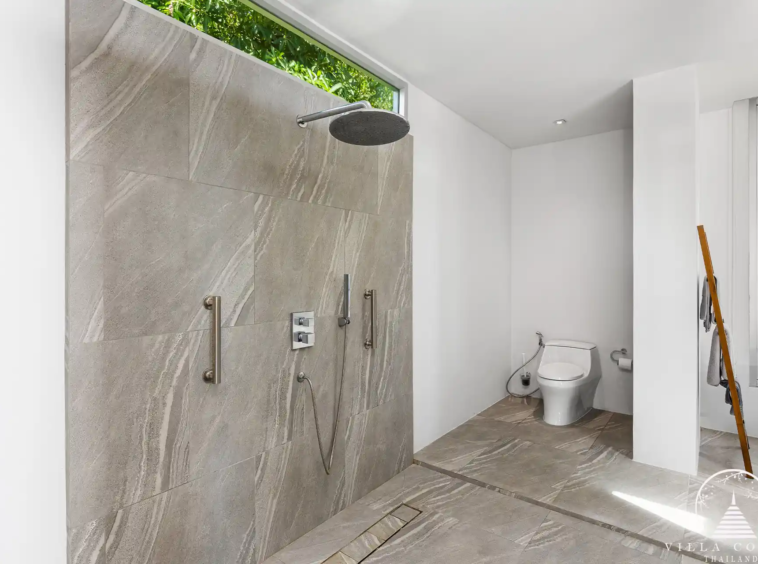 Outdoor shower area at Villa Nova at Layan Hillside with natural stone finishes and lush greenery.