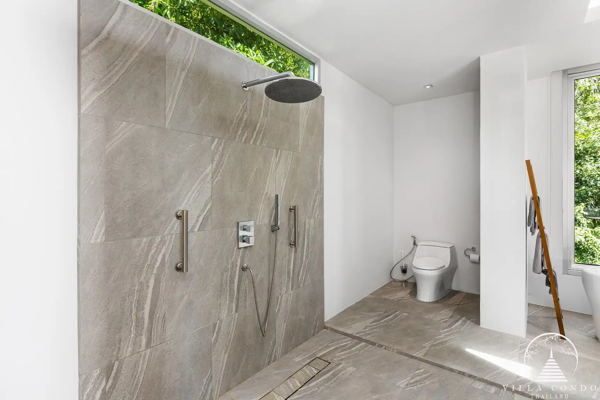 Outdoor shower area at Villa Nova at Layan Hillside with natural stone finishes and lush greenery.