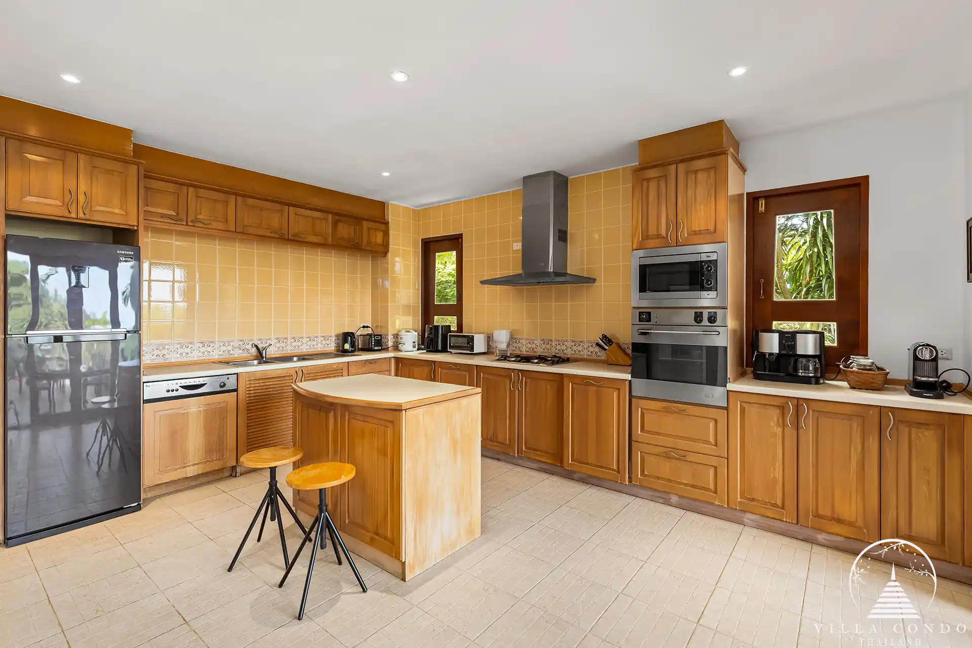 Modern fully-equipped kitchen at Nakathani Villa Estate Kamala Beach with a breakfast bar and cooking island.