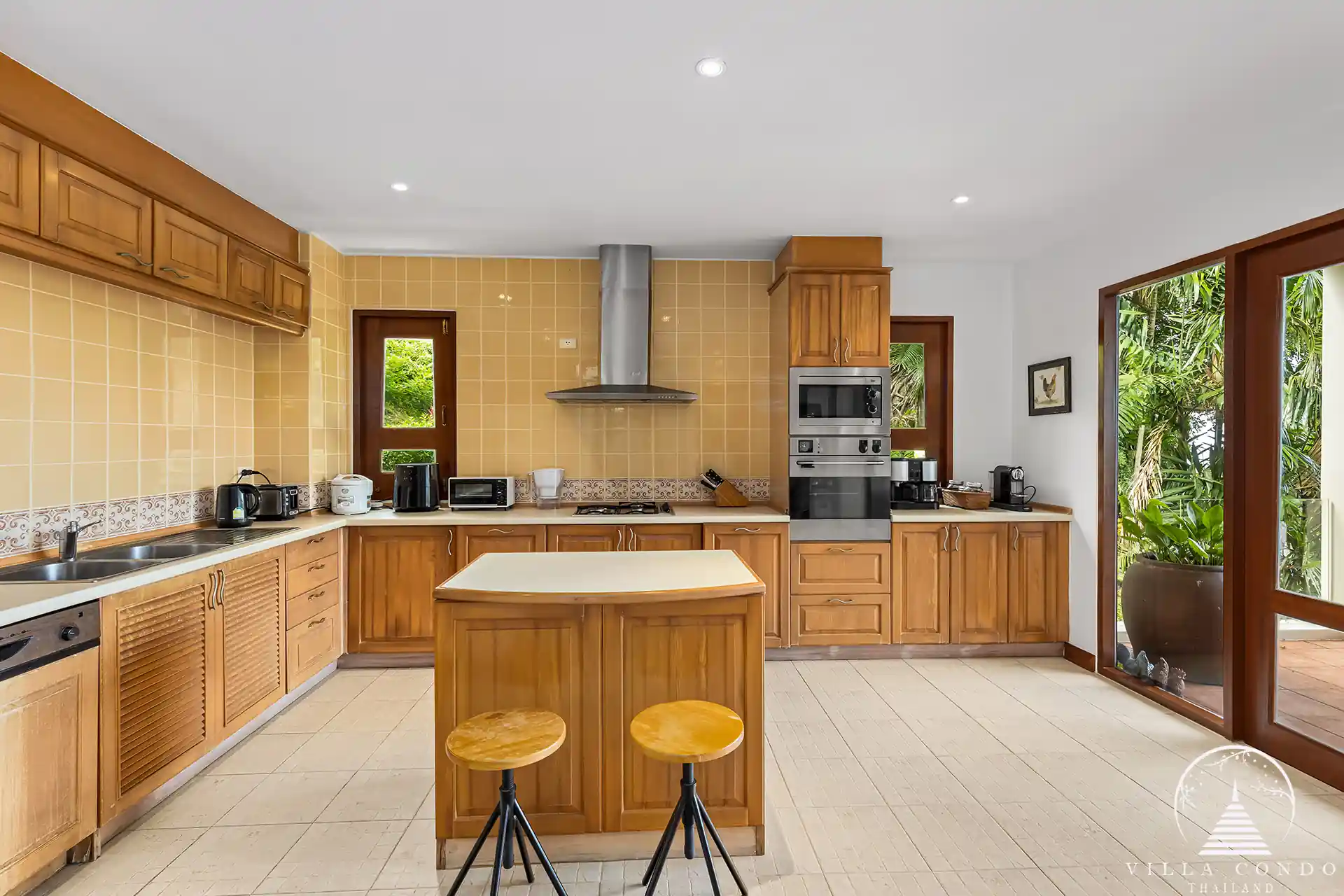 Modern fully-equipped kitchen at Nakathani Villa Estate Kamala Beach with a breakfast bar and cooking island.