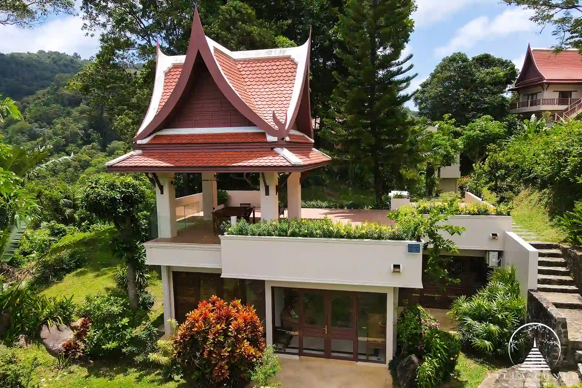 Exterior view of Nakathani Villa Estate Kamala Beach surrounded by tropical greenery and overlooking Thavorn Bay.