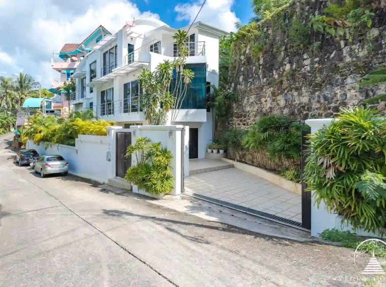 Side view of White Villa Patong with modern architecture and lush greenery.
