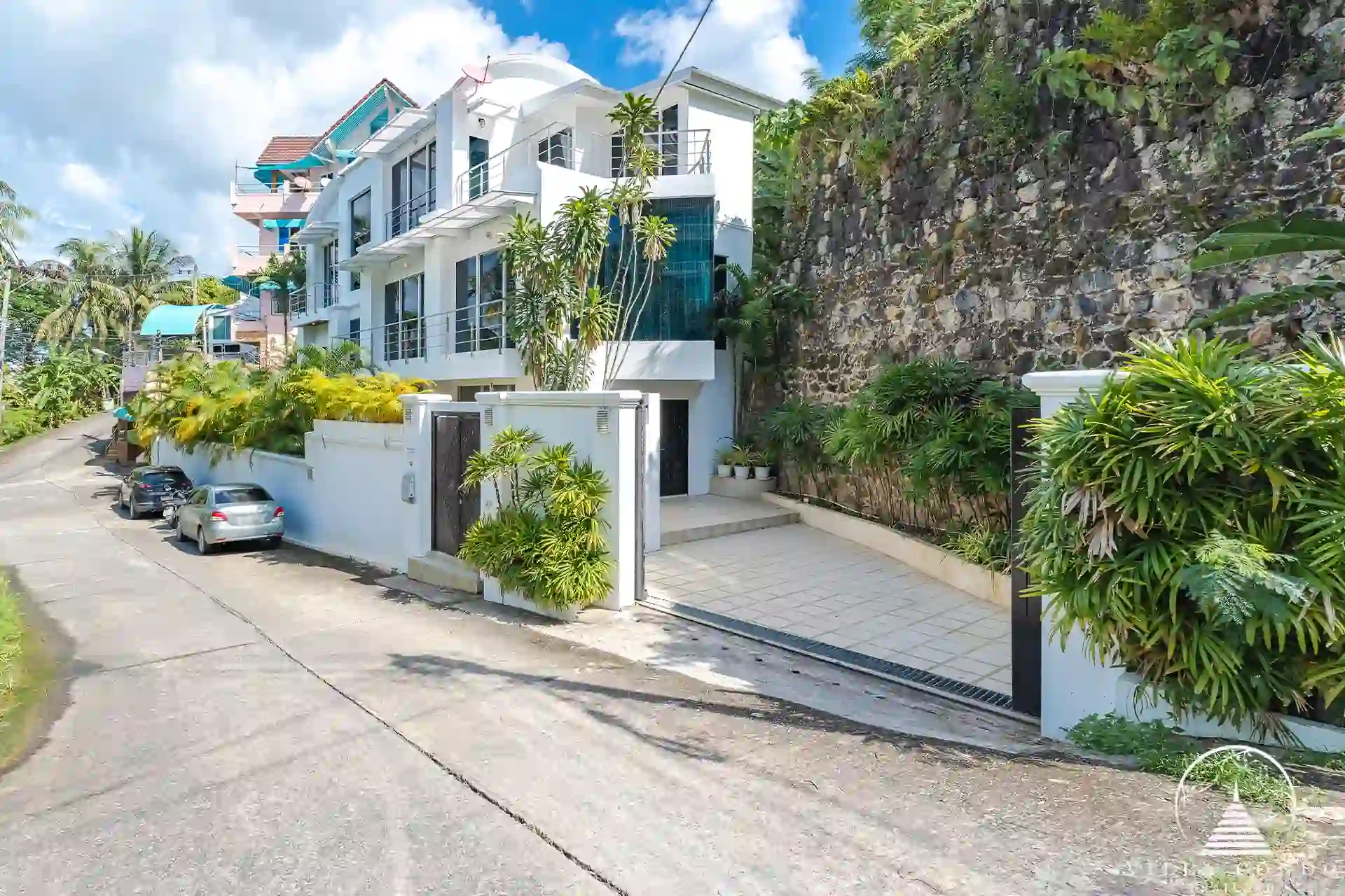 Side view of White Villa Patong with modern architecture and lush greenery.