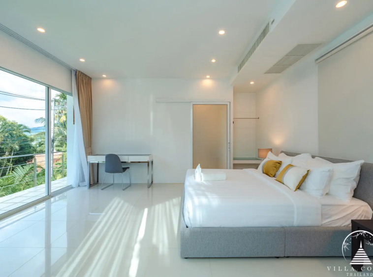 Spacious bedroom in White Villa Patong with balcony and sea view.